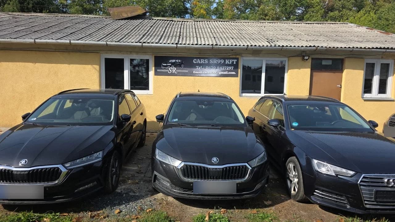 A CARS SR99 Kft. telephelyének épülete a cégtáblával, előtte három parkoló autó